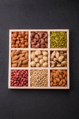 Ahşap bir kutunun içinde macadamia, çam, kaju, fındık, fıstık ve fıstık karışımı.