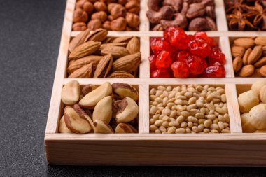 Ahşap bir kutunun içinde macadamia, çam, kaju, fındık, fıstık ve fıstık karışımı.