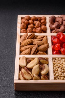 Ahşap bir kutunun içinde macadamia, çam, kaju, fındık, fıstık ve fıstık karışımı.