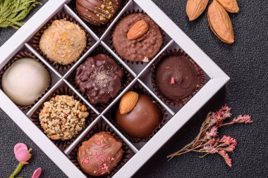 Koyu beton arka planda farklı dolgu ve serpiştirilmiş ev yapımı çikolatalı şekerler.