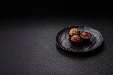 Koyu beton arka planda farklı dolgu ve serpiştirilmiş ev yapımı çikolatalı şekerler.