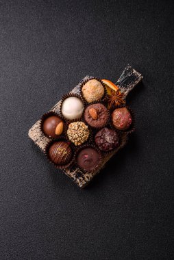 Koyu beton arka planda farklı dolgu ve serpiştirilmiş ev yapımı çikolatalı şekerler.
