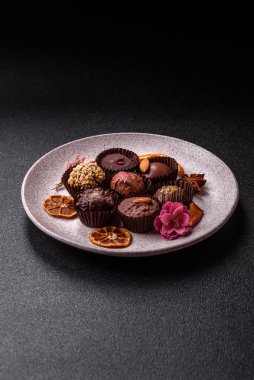 Koyu beton arka planda farklı dolgu ve serpiştirilmiş ev yapımı çikolatalı şekerler.