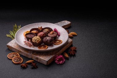 Koyu beton arka planda farklı dolgu ve serpiştirilmiş ev yapımı çikolatalı şekerler.