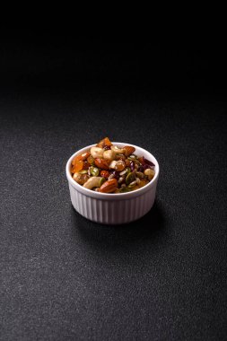 Ballı fındık, ceviz, fındık, çam fıstığı ve kurutulmuş meyveler koyu beton arka planda seramik kasede.