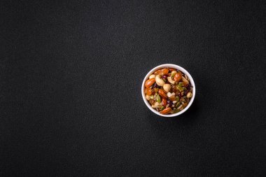 Ballı fındık, ceviz, fındık, çam fıstığı ve kurutulmuş meyveler koyu beton arka planda seramik kasede.