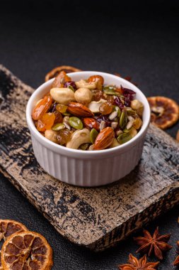 Ballı fındık, ceviz, fındık, çam fıstığı ve kurutulmuş meyveler koyu beton arka planda seramik kasede.