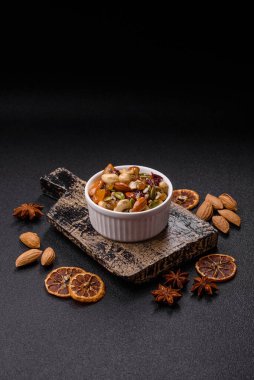 Ballı fındık, ceviz, fındık, çam fıstığı ve kurutulmuş meyveler koyu beton arka planda seramik kasede.