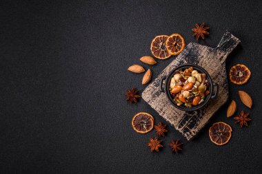 Ballı fındık, ceviz, fındık, çam fıstığı ve kurutulmuş meyveler koyu beton arka planda seramik kasede.