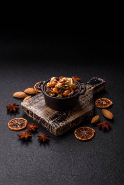 Ballı fındık, ceviz, fındık, çam fıstığı ve kurutulmuş meyveler koyu beton arka planda seramik kasede.