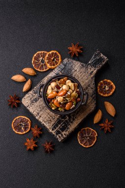 Ballı fındık, ceviz, fındık, çam fıstığı ve kurutulmuş meyveler koyu beton arka planda seramik kasede.