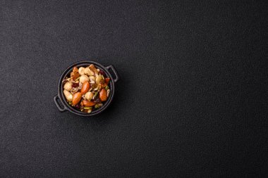 Ballı fındık, ceviz, fındık, çam fıstığı ve kurutulmuş meyveler koyu beton arka planda seramik kasede.