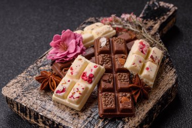 Çok renkli çikolatalar pembe, beyaz, kahverengi, koyu beton arka plan