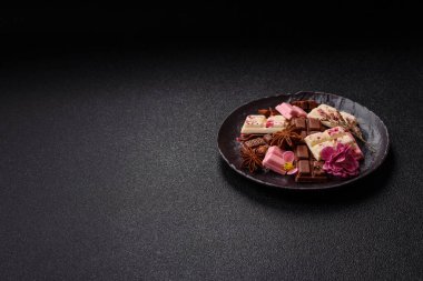 Çok renkli çikolatalar pembe, beyaz, kahverengi, koyu beton arka plan