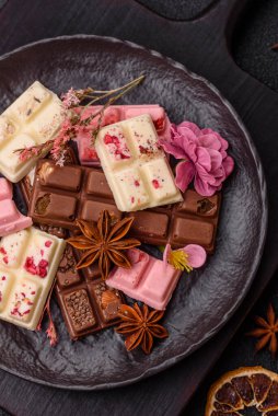 Çok renkli çikolatalar pembe, beyaz, kahverengi, koyu beton arka plan