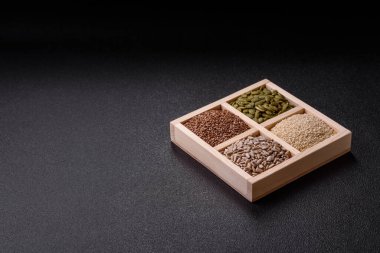 Ayçiçeği, balkabağı, keten ve susam tohumları, vejetaryen ve vejetaryen yemekleri yapmak için gerekli malzemeler olarak ahşap bir kutunun içinde.