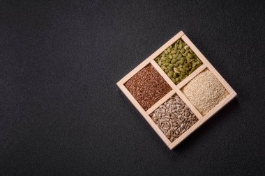 Ayçiçeği, balkabağı, keten ve susam tohumları, vejetaryen ve vejetaryen yemekleri yapmak için gerekli malzemeler olarak ahşap bir kutunun içinde.