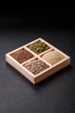 Ayçiçeği, balkabağı, keten ve susam tohumları, vejetaryen ve vejetaryen yemekleri yapmak için gerekli malzemeler olarak ahşap bir kutunun içinde.