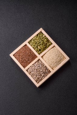 Ayçiçeği, balkabağı, keten ve susam tohumları, vejetaryen ve vejetaryen yemekleri yapmak için gerekli malzemeler olarak ahşap bir kutunun içinde.