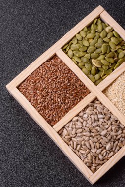 Ayçiçeği, balkabağı, keten ve susam tohumları, vejetaryen ve vejetaryen yemekleri yapmak için gerekli malzemeler olarak ahşap bir kutunun içinde.