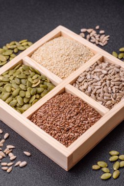 Ayçiçeği, balkabağı, keten ve susam tohumları, vejetaryen ve vejetaryen yemekleri yapmak için gerekli malzemeler olarak ahşap bir kutunun içinde.