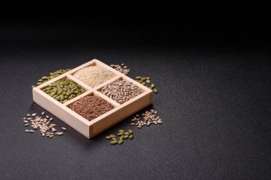 Ayçiçeği, balkabağı, keten ve susam tohumları, vejetaryen ve vejetaryen yemekleri yapmak için gerekli malzemeler olarak ahşap bir kutunun içinde.