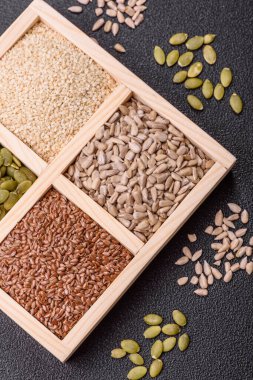 Ayçiçeği, balkabağı, keten ve susam tohumları, vejetaryen ve vejetaryen yemekleri yapmak için gerekli malzemeler olarak ahşap bir kutunun içinde.
