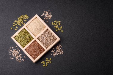 Ayçiçeği, balkabağı, keten ve susam tohumları, vejetaryen ve vejetaryen yemekleri yapmak için gerekli malzemeler olarak ahşap bir kutunun içinde.