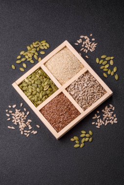 Ayçiçeği, balkabağı, keten ve susam tohumları, vejetaryen ve vejetaryen yemekleri yapmak için gerekli malzemeler olarak ahşap bir kutunun içinde.