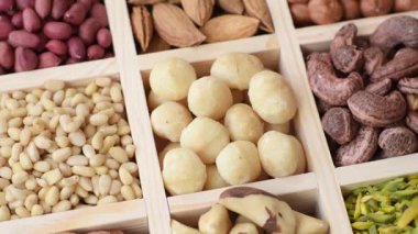 Ahşap bir kutunun içinde macadamia, çam, kaju, fındık, fıstık ve fıstık karışımı.