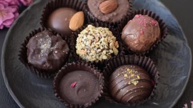 Koyu beton arka planda farklı dolgu ve serpiştirilmiş ev yapımı çikolatalı şekerler.