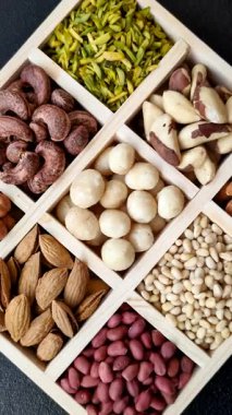 Ahşap bir kutunun içinde macadamia, çam, kaju, fındık, fıstık ve fıstık karışımı.
