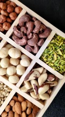Ahşap bir kutunun içinde macadamia, çam, kaju, fındık, fıstık ve fıstık karışımı.