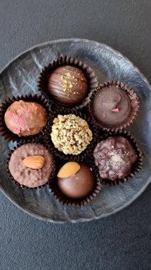 Koyu beton arka planda farklı dolgu ve serpiştirilmiş ev yapımı çikolatalı şekerler.