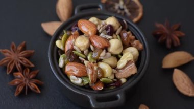 Ballı fındık, ceviz, fındık, çam fıstığı ve kurutulmuş meyveler koyu beton arka planda seramik kasede.