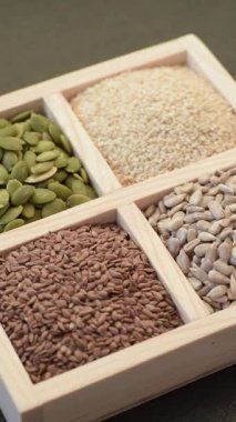 Ayçiçeği, balkabağı, keten ve susam tohumları, vejetaryen ve vejetaryen yemekleri yapmak için gerekli malzemeler olarak ahşap bir kutunun içinde.