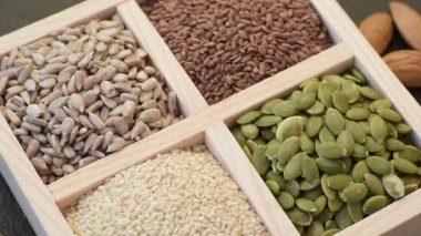 Ayçiçeği, balkabağı, keten ve susam tohumları, vejetaryen ve vejetaryen yemekleri yapmak için gerekli malzemeler olarak ahşap bir kutunun içinde.