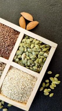 Ayçiçeği, balkabağı, keten ve susam tohumları, vejetaryen ve vejetaryen yemekleri yapmak için gerekli malzemeler olarak ahşap bir kutunun içinde.