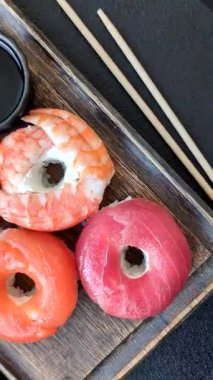 Somon, karides, ton balığı, tuz, baharat ve soya soslu donut şeklinde suşi ruloları.
