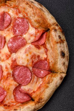 Sosisli, peynirli, domatesli, tuzlu ve baharatlı biberli pizza.