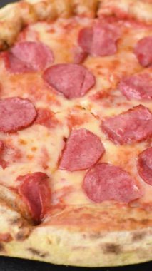 Sosisli, peynirli, domatesli, tuzlu ve baharatlı biberli pizza.