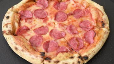 Sosisli, peynirli, domatesli, tuzlu ve baharatlı biberli pizza.