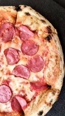 Sosisli, peynirli, domatesli, tuzlu ve baharatlı biberli pizza.