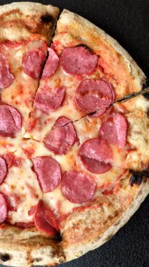 Sosisli, peynirli, domatesli, tuzlu ve baharatlı biberli pizza.