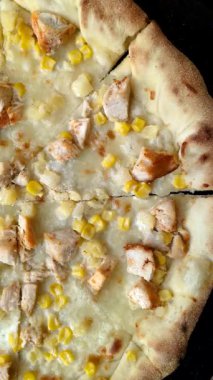Koyu beton arka planda tavuk, ananas, mısır ve peynirli Hawaii pizzası.