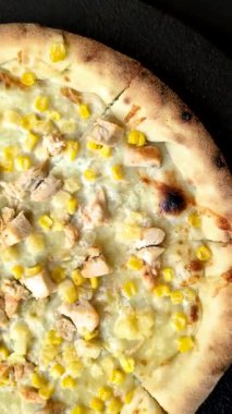 Koyu beton arka planda tavuk, ananas, mısır ve peynirli Hawaii pizzası.