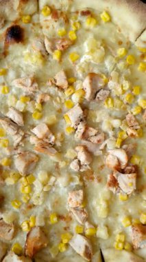 Koyu beton arka planda tavuk, ananas, mısır ve peynirli Hawaii pizzası.
