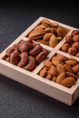 İçinde fındık bademleri, kabuklu bademler, cevizler, fındıklar olan tahta kutu.