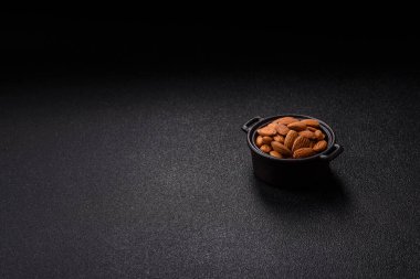 Koyu beton arka planda kavrulmuş ya da soyulmuş bademler.