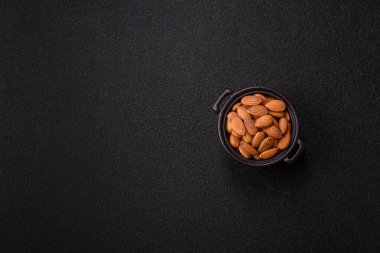 Koyu beton arka planda kavrulmuş ya da soyulmuş bademler.